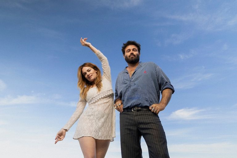 Promotional portrait of Australian folk-pop duo Angus & Julia Stone standing outdoors against a bright blue sky.